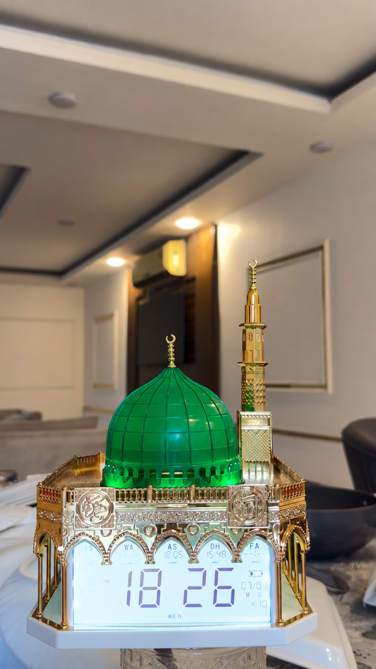 ساعة أذان رقمية بتصميم مستوحى من المسجد النبوي الشريف، تتميز بقبة خضراء مضاءة ومئذنة ذهبية مع شاشة عرض رقمية لمواقيت الصلاة والتاريخ